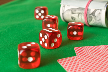 Dice, playing cards and twisted 100 dollar bills on the green table. Winning concept
