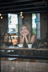 Fototapeta na wymiar Portrait of young woman smiling in coffee shop cafe
