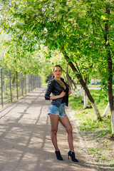 Charming woman dressed in a leather jacket standing on the road