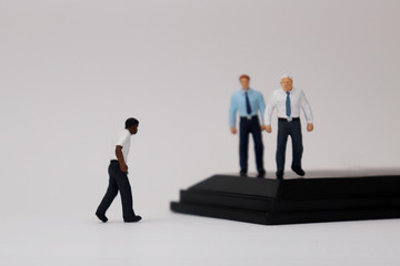 Fototapeta premium The concept of racism in business. Miniature&nbsp;people&nbsp;of&nbsp;different&nbsp;races.