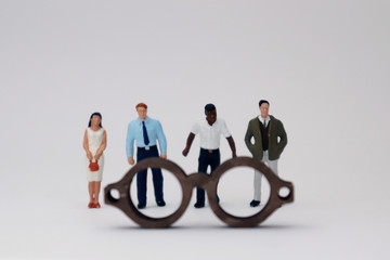 A concept of diversity and prejudice. Various miniature people standing behind the glasses.