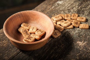 Runes in a wooden plate on a textured old textured wooden surface