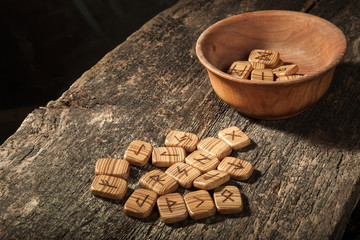 Runes in a wooden plate on a textured old textured wooden surface