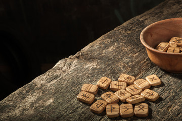 Runes in a wooden plate on a textured old textured wooden surface