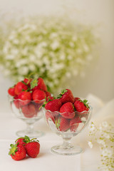 Strawberries in a jelly glass on a white background.