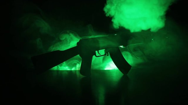 Silhouette of assault rifle on toned foggy background. War or antiterrorism concept. Russian military weapon on table. Slider shot