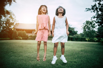 Two little girls friends playing funny in the park