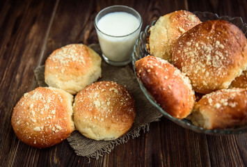 Homemade sweet yeast buns with apple jam and glass of milk on dark wooden background with copy space.