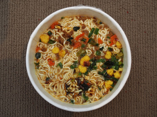 Cooked instant cup noodle on brown background 