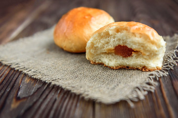 Homemade sweet yeast buns with apple jam on dark wooden background.