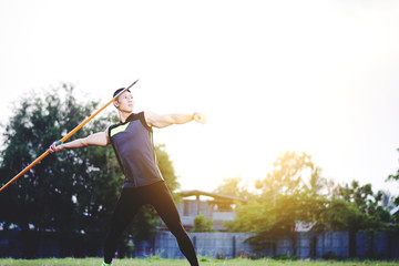 sportsman warming up and practicing javelin throw in yard