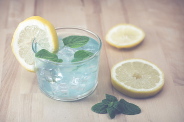 Gin and tonic blue with mint leaves, on wooden board