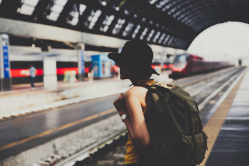 Silhouette Young backpacker hipster woman waiting for the train at platform in train station.