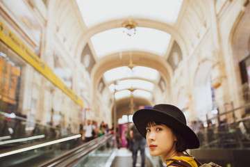 A backpacker standing in the walk way in the train station to the platform.