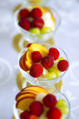 Healthy fresh fruit and berry salad with raspberries, pineapple, banana, grapes, apples and on a table outdoors slices of apple in glass.fruit background