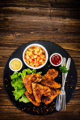 Chicken wings with French fries on wooden background 