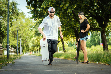 man with a skateboard shows a woman how to ride on a summer day © superelaks