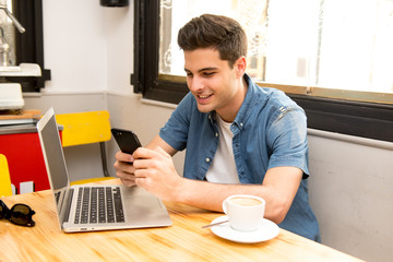 young student using his smart phone to read text while having a coffee