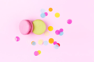 Pink and green macarons on pink background decorated with cinfetti. Top view.