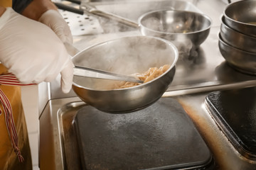 Male chef cooking pasta in restaurant kitchen, closeup