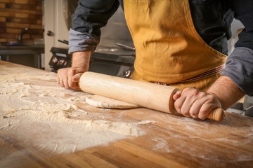 Male chef preparing dough for pizza in restaurant kitchen