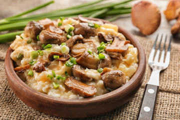 Bowl with risotto and mushrooms on table, closeup