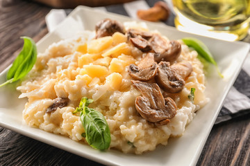Plate with risotto and mushrooms on wooden table, closeup