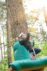 Fototapeta na wymiar Little girl riding zip wire in trekking tree park