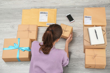 Woman preparing parcels for shipment to customer on floor
