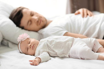 Fototapeta na wymiar Young father with cute baby sleeping on bed at home
