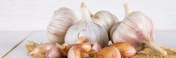 Garlic cloves and garlic bulb on a white wooden table.
