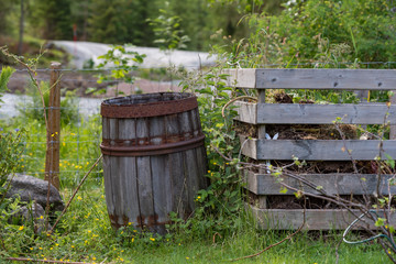 old wooden barrel standig beside a garden compost