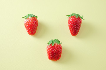 Tree strawberry fruits on yellow background.