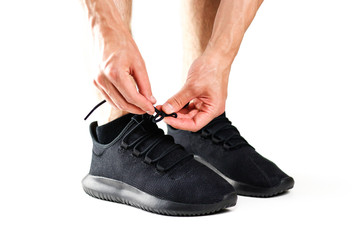A man tying his shoelaces on black sports shoes. For sports. Isolated on white background