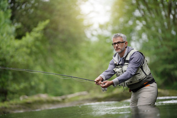 Fisherman fly-fishing in river