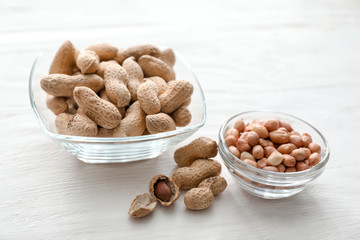 Bowls with tasty peanuts on wooden table