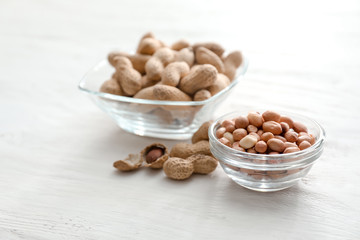 Bowls with tasty peanuts on wooden table