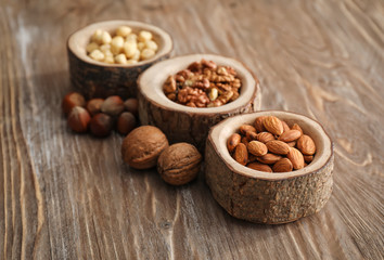 Bowls with various tasty nuts on wooden table