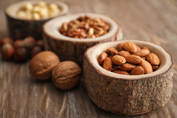 Bowls with various tasty nuts on wooden table