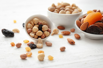 Bowls with various tasty nuts and dried fruits on wooden table