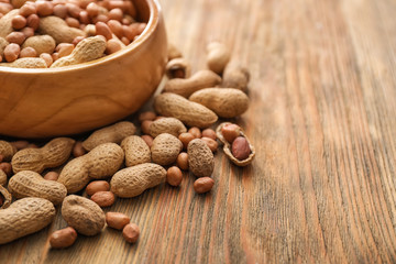 Bowl with tasty peanuts on wooden table