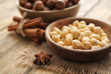 Bowl with tasty hazelnuts on wooden table