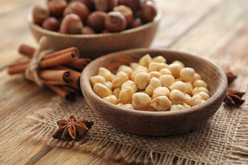 Bowl with tasty hazelnuts on wooden table