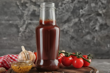 Fototapeta na wymiar Bottle with tasty tomato sauce and vegetables on wooden board