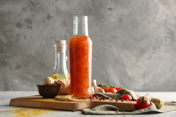 Bottle with tasty sauce and vegetables on wooden board