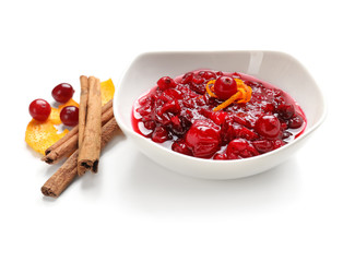 Bowl with tasty cranberry sauce  and cinnamon sticks on white background