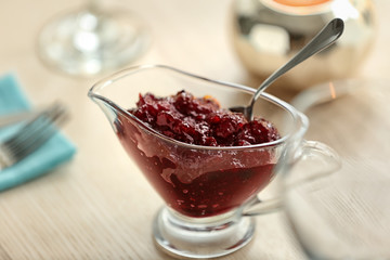 Gravy boat with tasty cranberry sauce on table