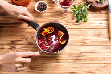 Woman preparing delicious cranberry sauce at table, top view