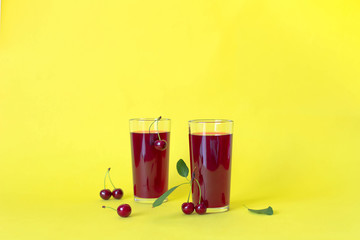 Cherry juice with cherry berries on yellow background.