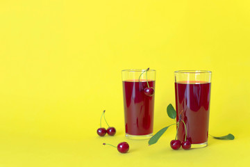 Cherry juice with cherry berries on yellow background.